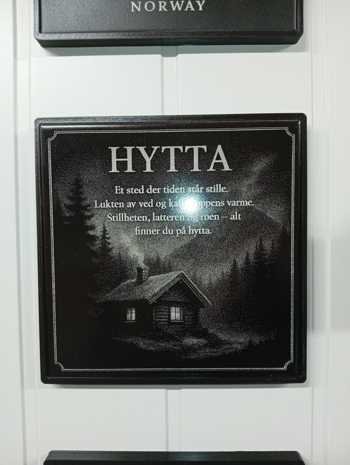 Vegghengt hytteskilt (20×20 cm keramisk flis) med lasergravert tekst og hyttemotiv.